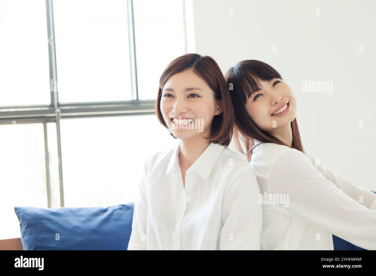 Two women in their 20s with their backs to each other Stock Photo - Alamy