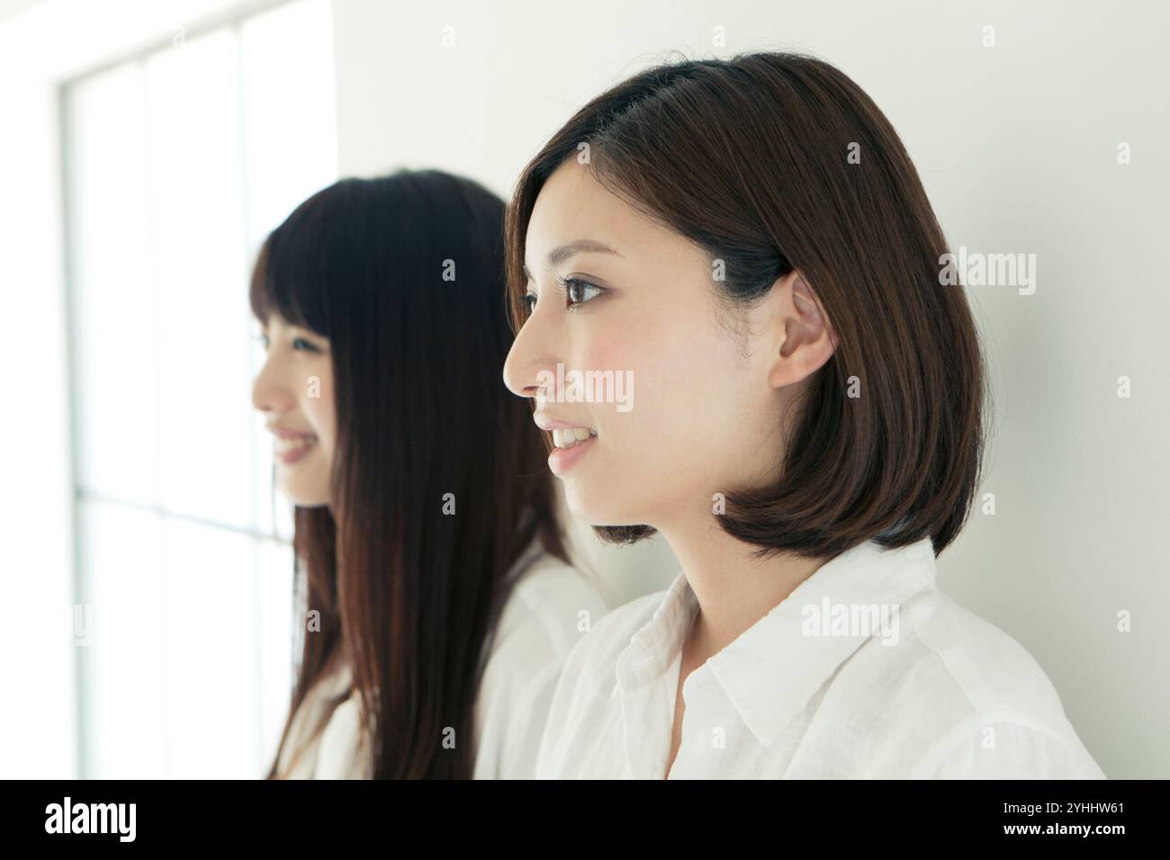 Two women in their 20s smiling in a friendly row Stock Photo - Alamy