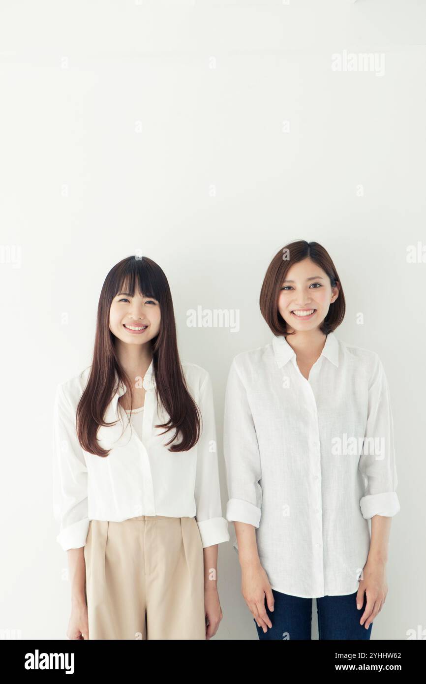 Two women in their 20s smiling in a friendly row Stock Photo - Alamy