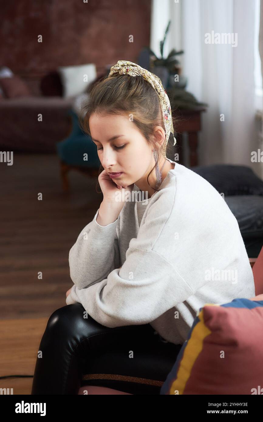 a portrait of a teenage girl sitting in a comfortable chair at home ...