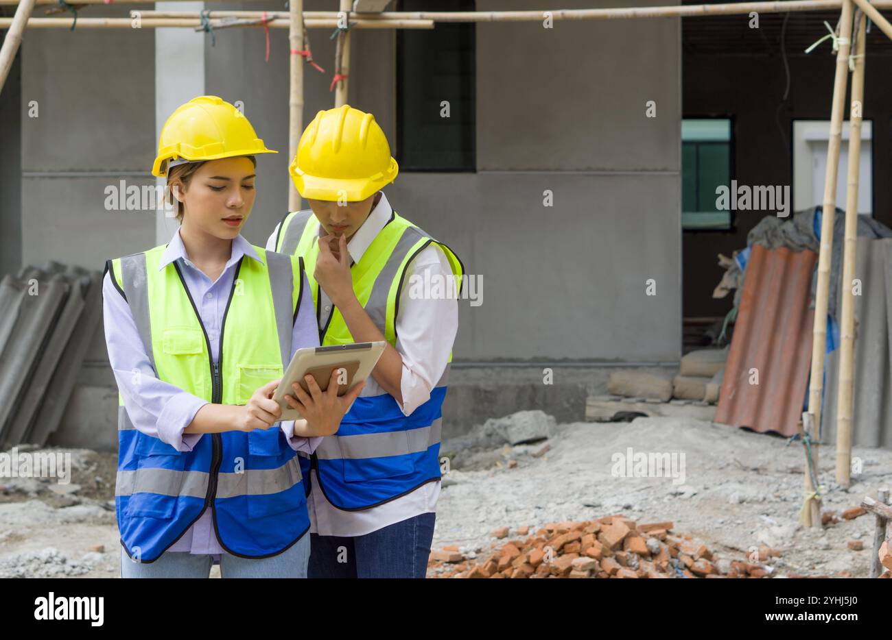 Young engineer in a construction helmet and safety vest explaining to ...