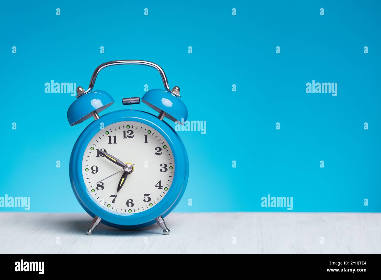 Old-fashioned alarm clock on blue background Stock Photo - Alamy