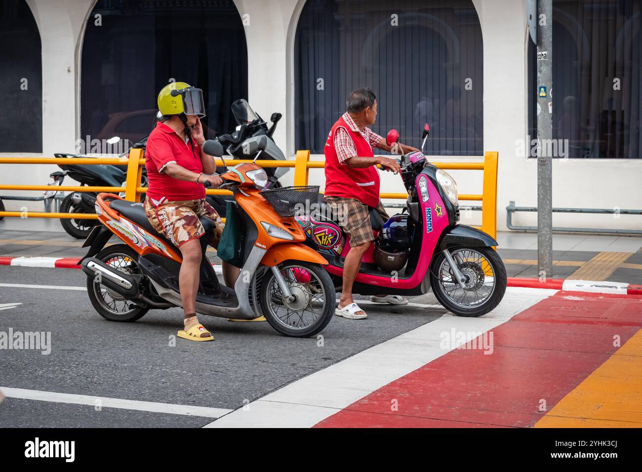 Local thai people ride motorbike. Motorcyclists awaiting traffic light on the road. People riding their motorbikes in old town Phuket Thailand-Street Stock Photo