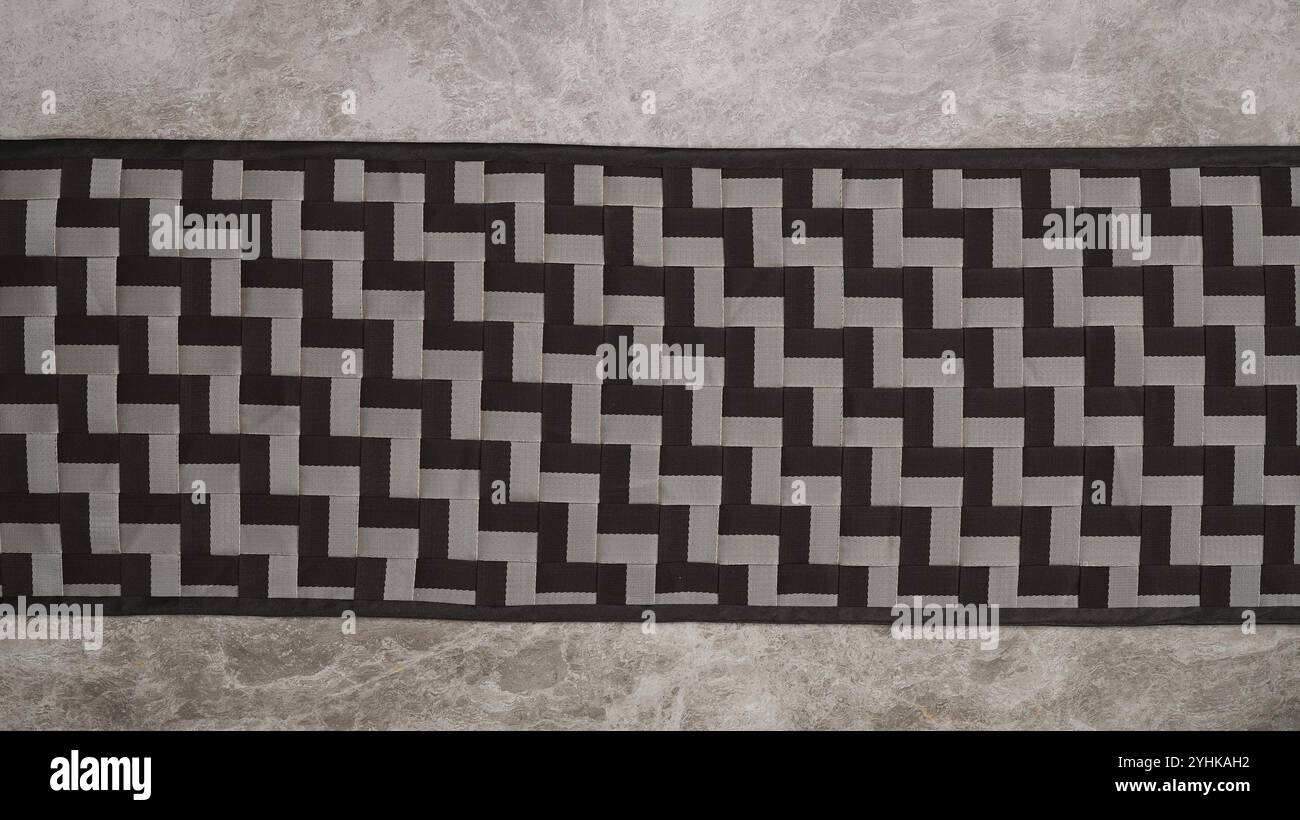 A rectangular piece with a black and gray geometric zigzag pattern on a textured surface Stock Photo