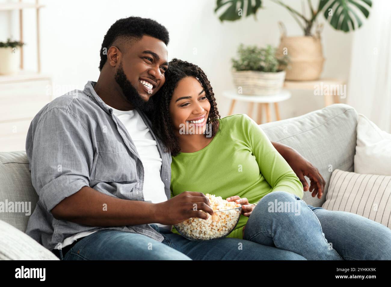 Relaxed african american couple watching tv, sitting on couch with ...