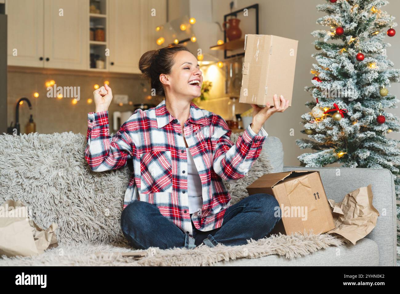 Cheerful Caucasian woman sitting on a sofa at home, celebrating the ...