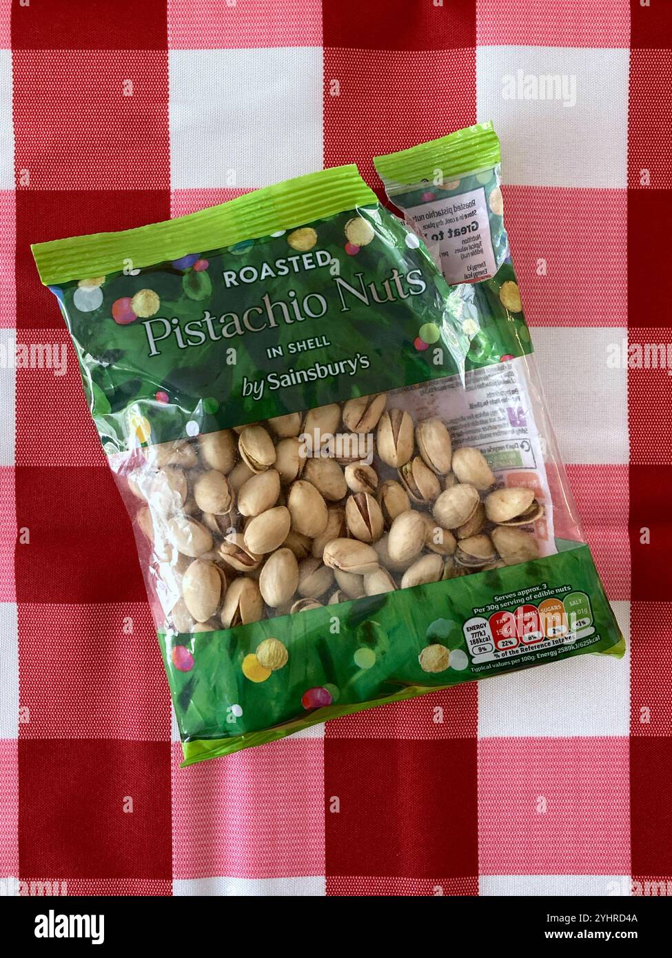 Opened bag of Roasted Pistachio nuts on a red checked tablecloth - Smartphone Captured Stock Image