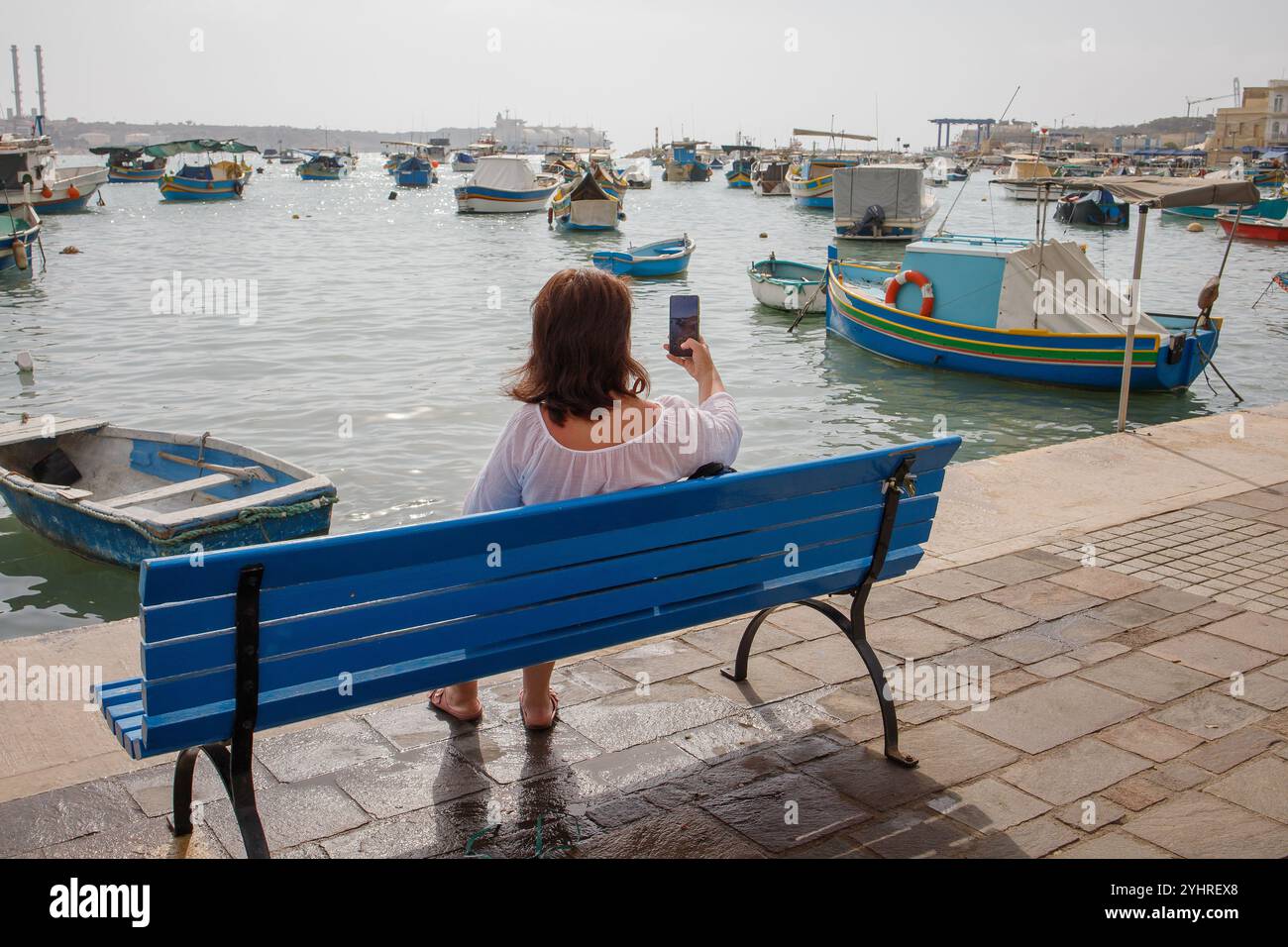 Woman traveler taking pictures in touristic fishing village Marsaxlokk in Malta Stock Photo