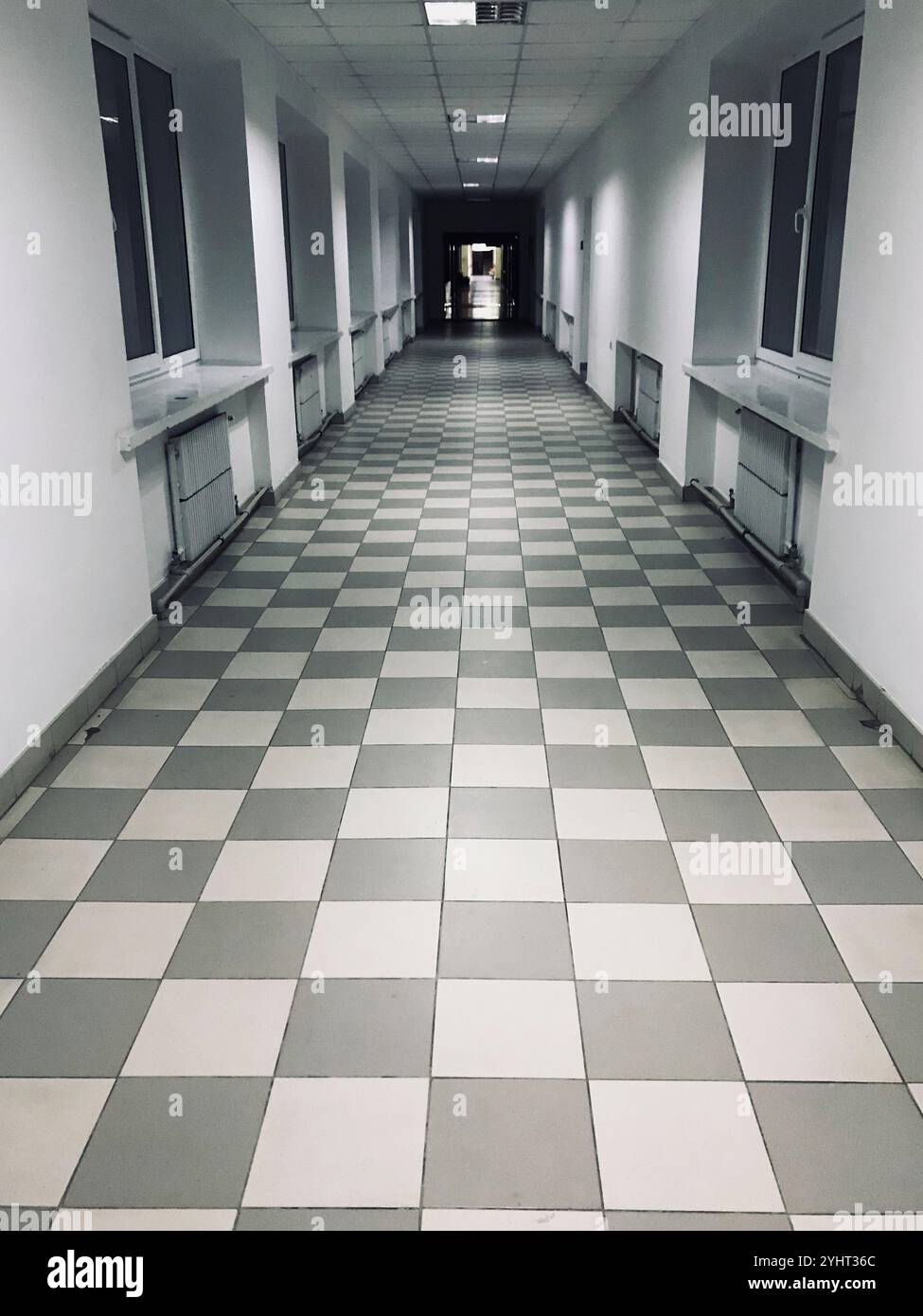 A long, empty corridor with checkerboard-patterned tiles and large ...