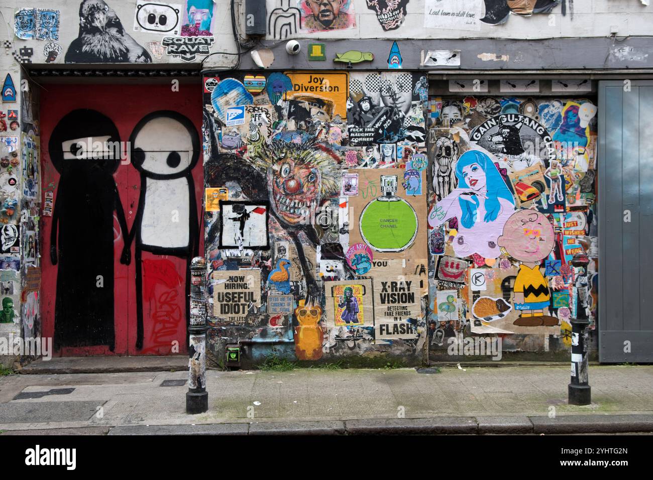 Street wall art UK. Playfully depicting two Muslim women one wearing her traditional black Abaya and Niqab and the other with no face covering or a white face covering allowing just the eyes to see. Just off Brick Lane, a club doorway surrounded by graffiti. Artwork by graffiti artist Stik. Princelet Street,Tower Hamlets, East End London England UK 2020s 2024 HOMER SYKES Stock Photo