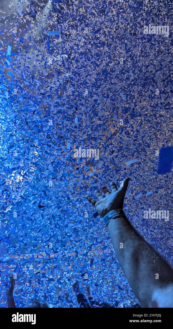 A male hand reaches upwards towards a confetti explosion. - Smartphone Captured Stock Image