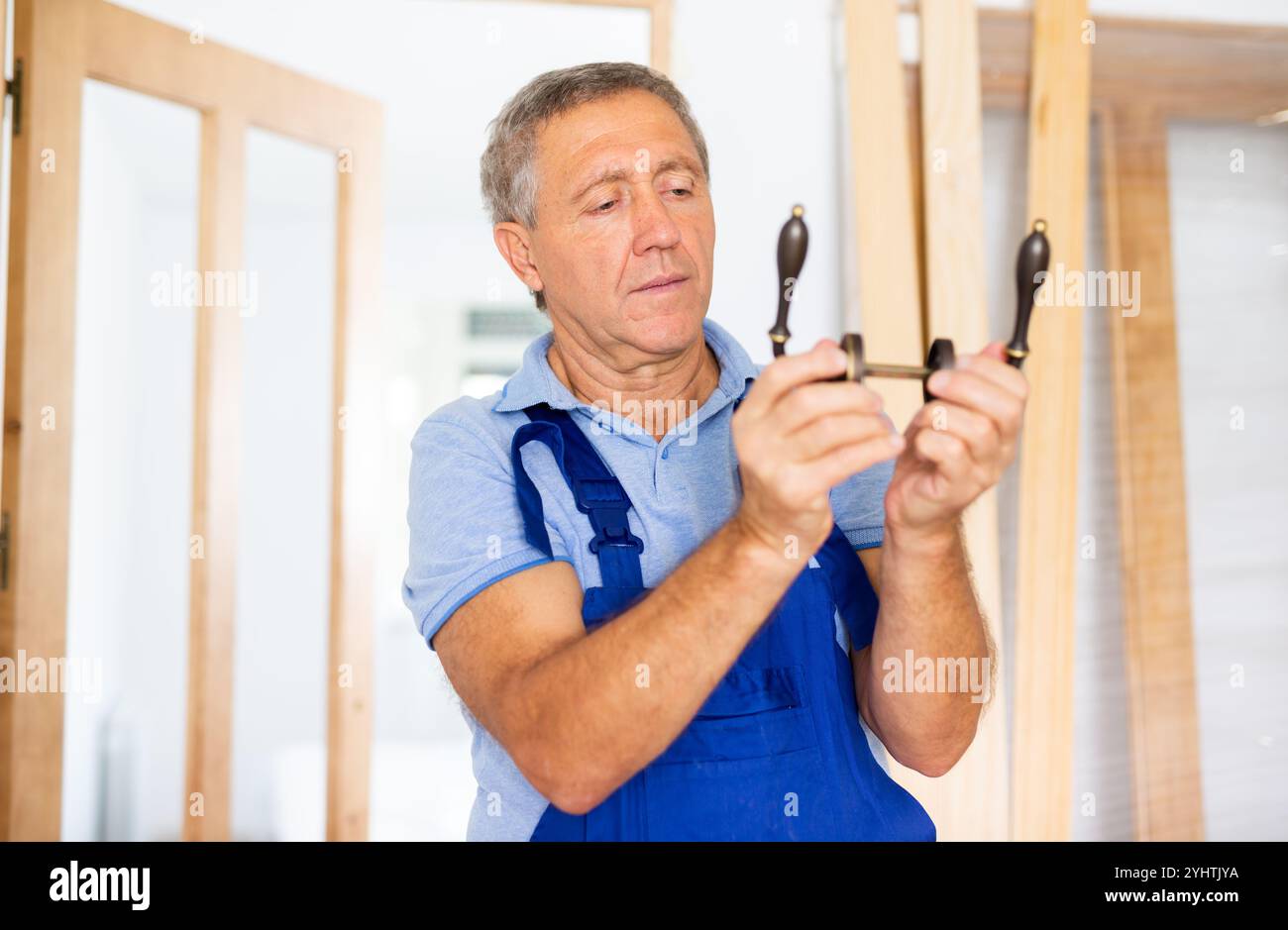Image showcasing Professional door installer checks operation of bronze door handles ...