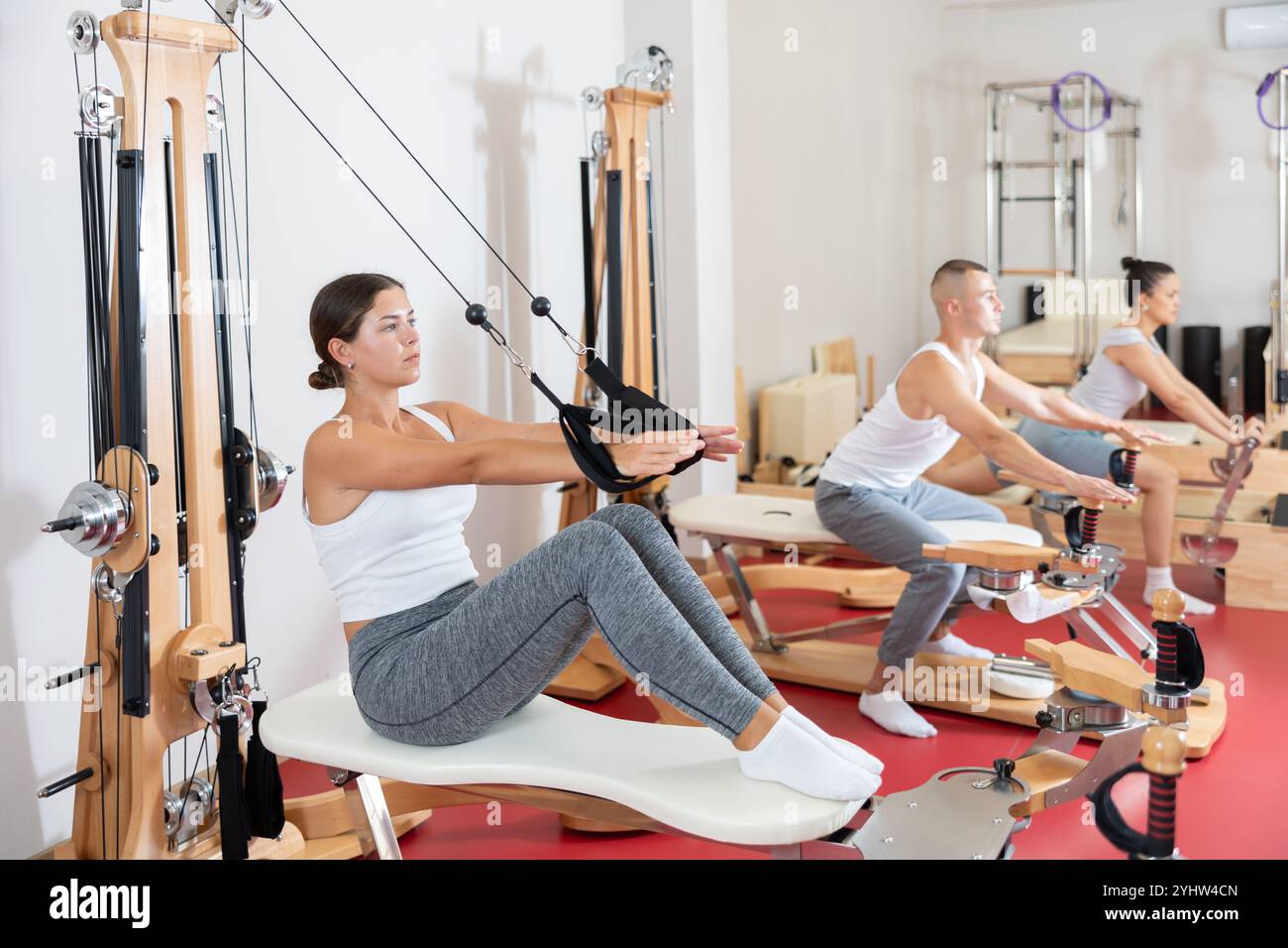 Sportive young girl training her arms pulling handle of cable exercise ...