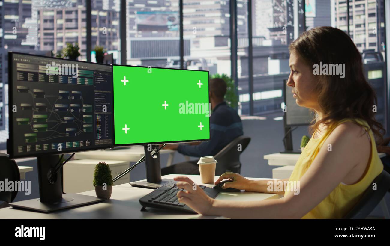 Computer scientist working, doing software debugging using mockup PC, troubleshooting errors. Woman in office fixing coding issues using green screen computer, solving tasks, camera B Stock Photo