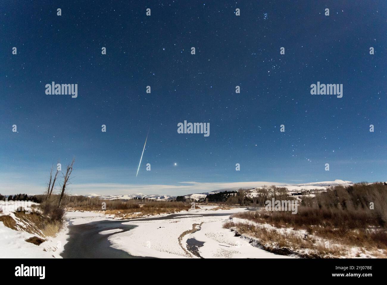 A Geminid Meteor streaks through the sky above the Gros Ventre River in Grand Teton National Park, Wyoming. Stock Photo