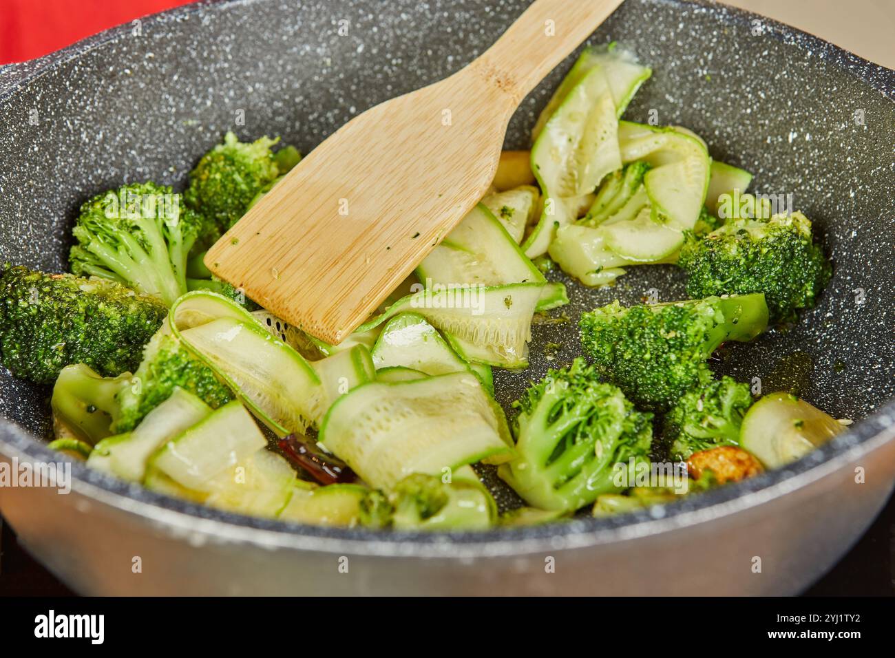 Broccoli and zucchini are stirred in hot oil, blending flavors and aromas in a vibrant, healthy dish preparation. Stock Photo