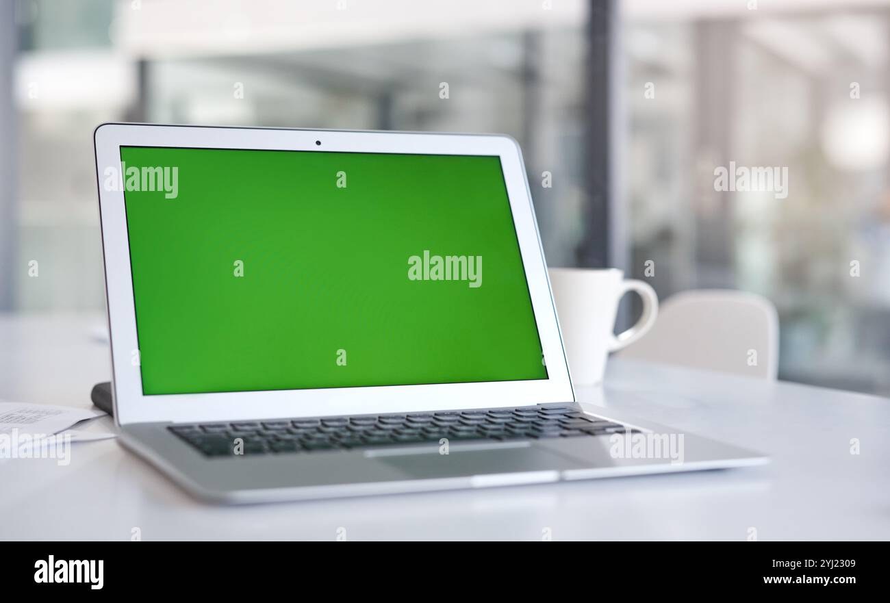 Green screen, desk and laptop for mockup space, advertising promo or placeholder in office. Display, computer or monitor with chroma key for design Stock Photo