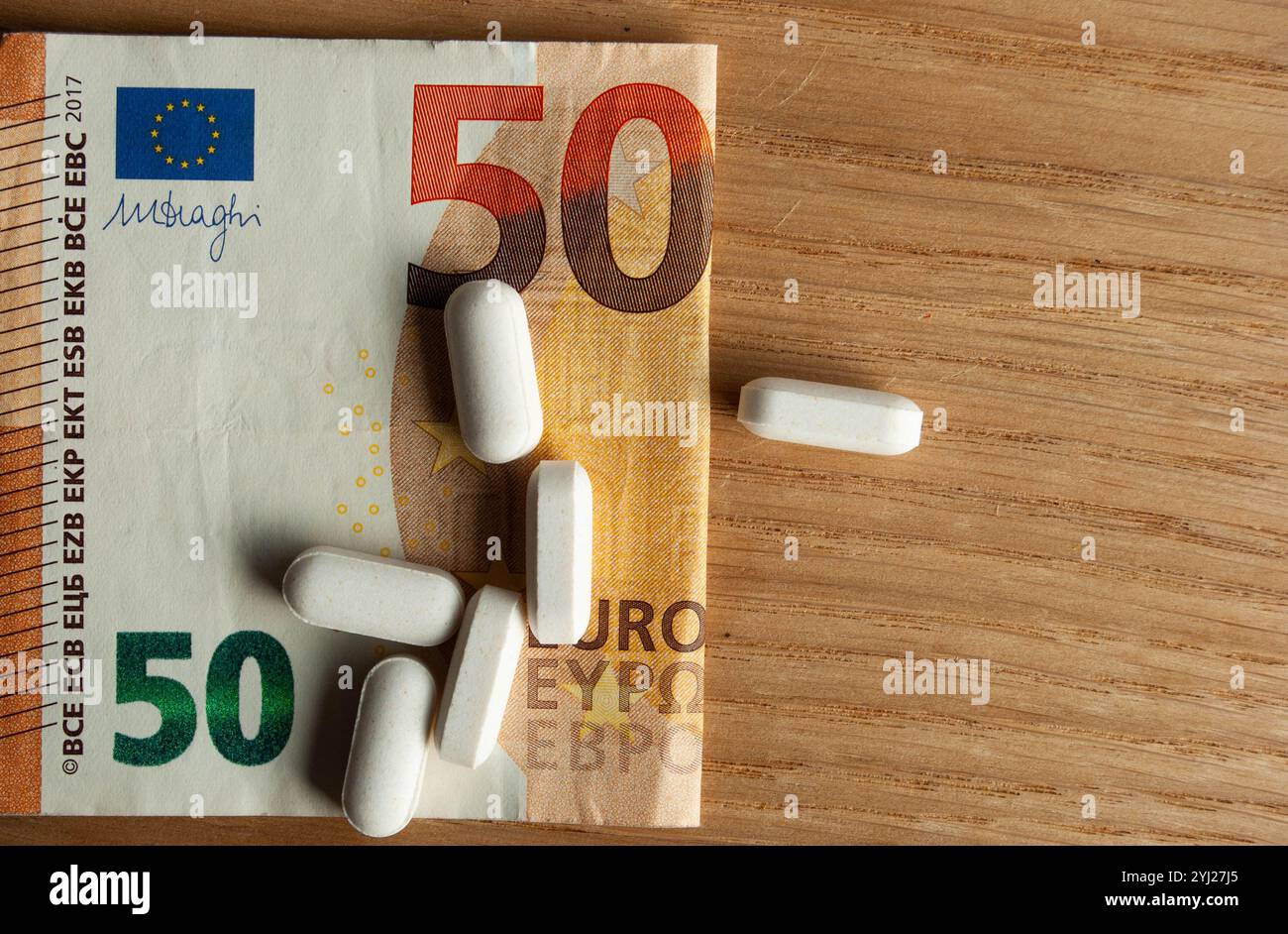 White pills placed on a banknote symbolizing the high cost of healthcare. Stock Photo