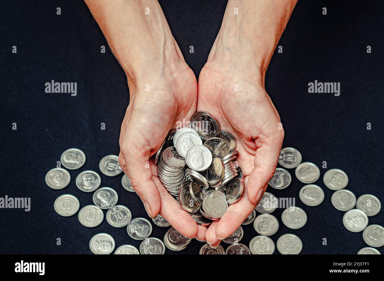 Close up of silver coins in female hands on black studio background ...