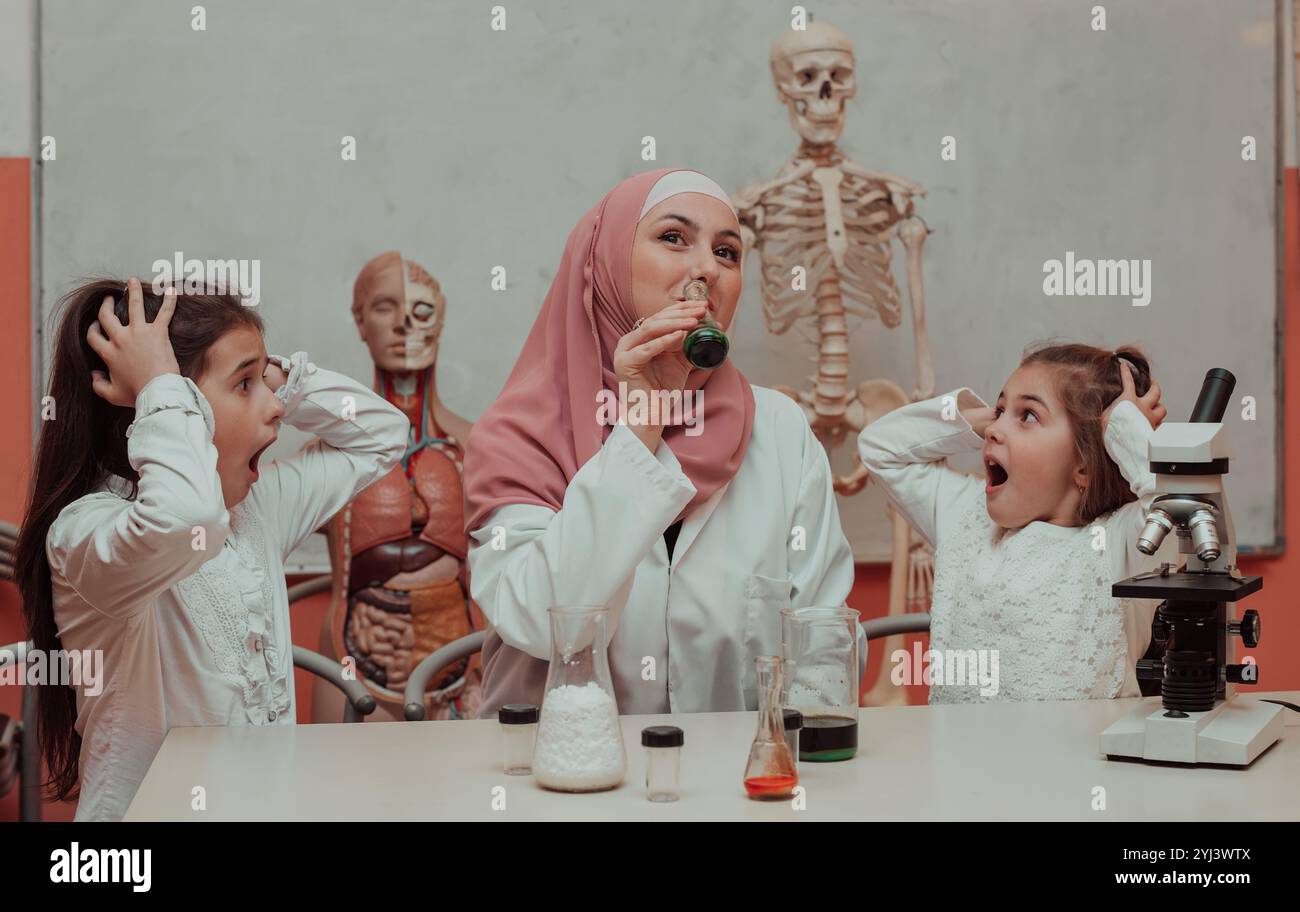 Kids scientists with a female Muslim teacher have fun while doing chemistry science experiments in the school lab.  Stock Photo