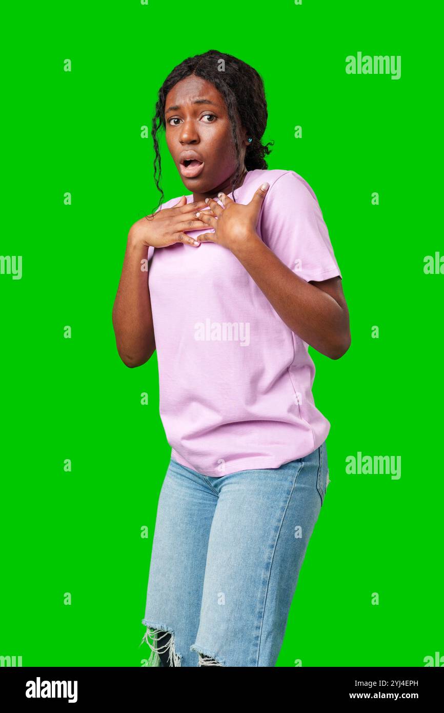 Surprised young woman against a vibrant green background expressing astonishment or shock Stock Photo