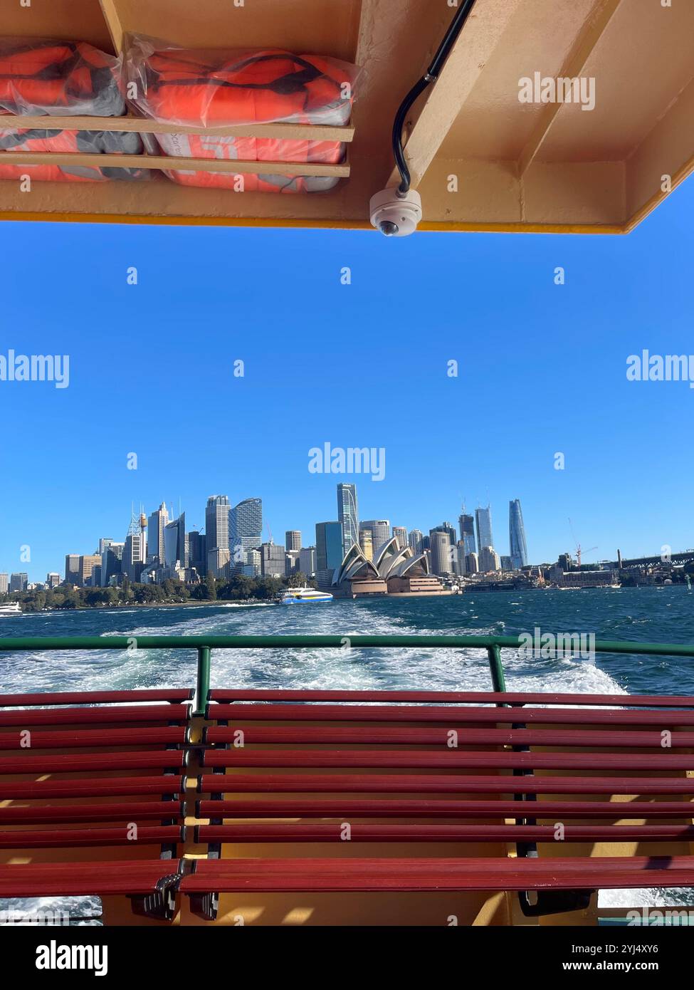 View from the back of a ferry, with waves trailing behind and the stunning Sydney city skyline in the distance. - Smartphone Captured Stock Image