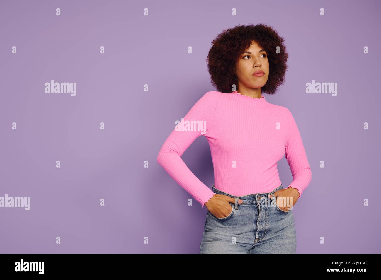 A young African American woman with curly hair dressed in casual pink ...