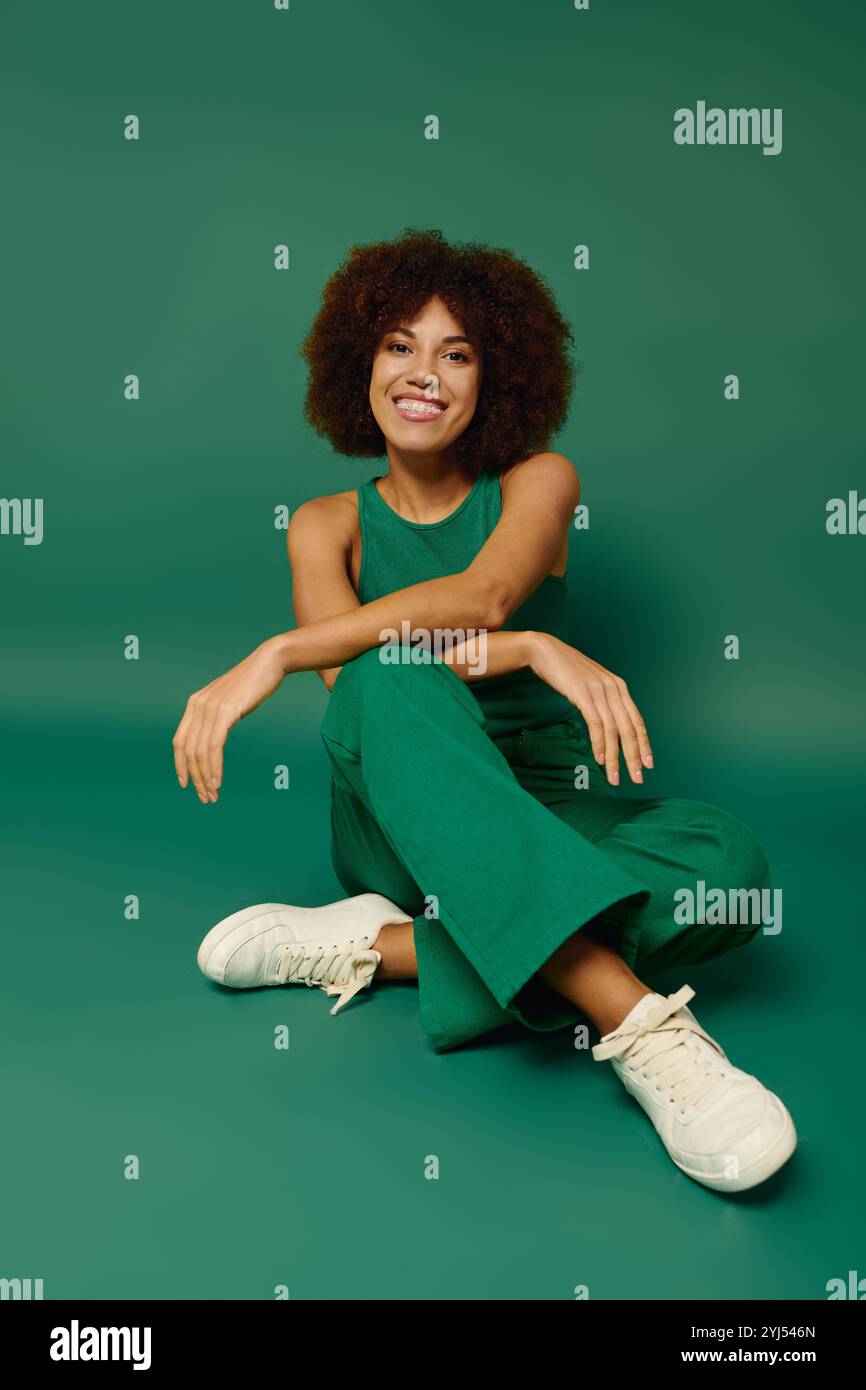 A cheerful young woman with curly hair expresses her joy while seated ...