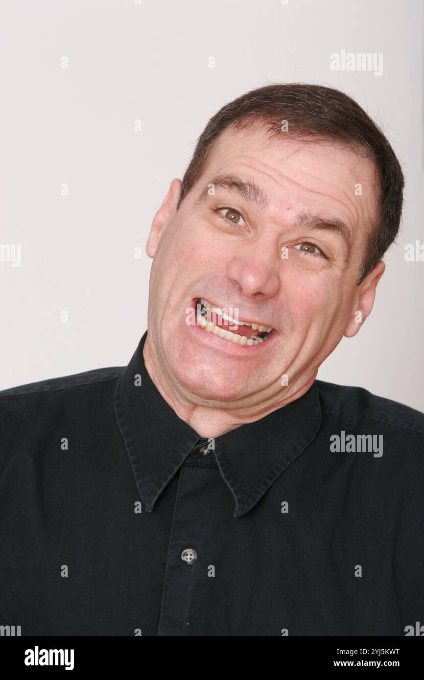 Middle-aged man, with dark hair on white background, makes unusual face ...