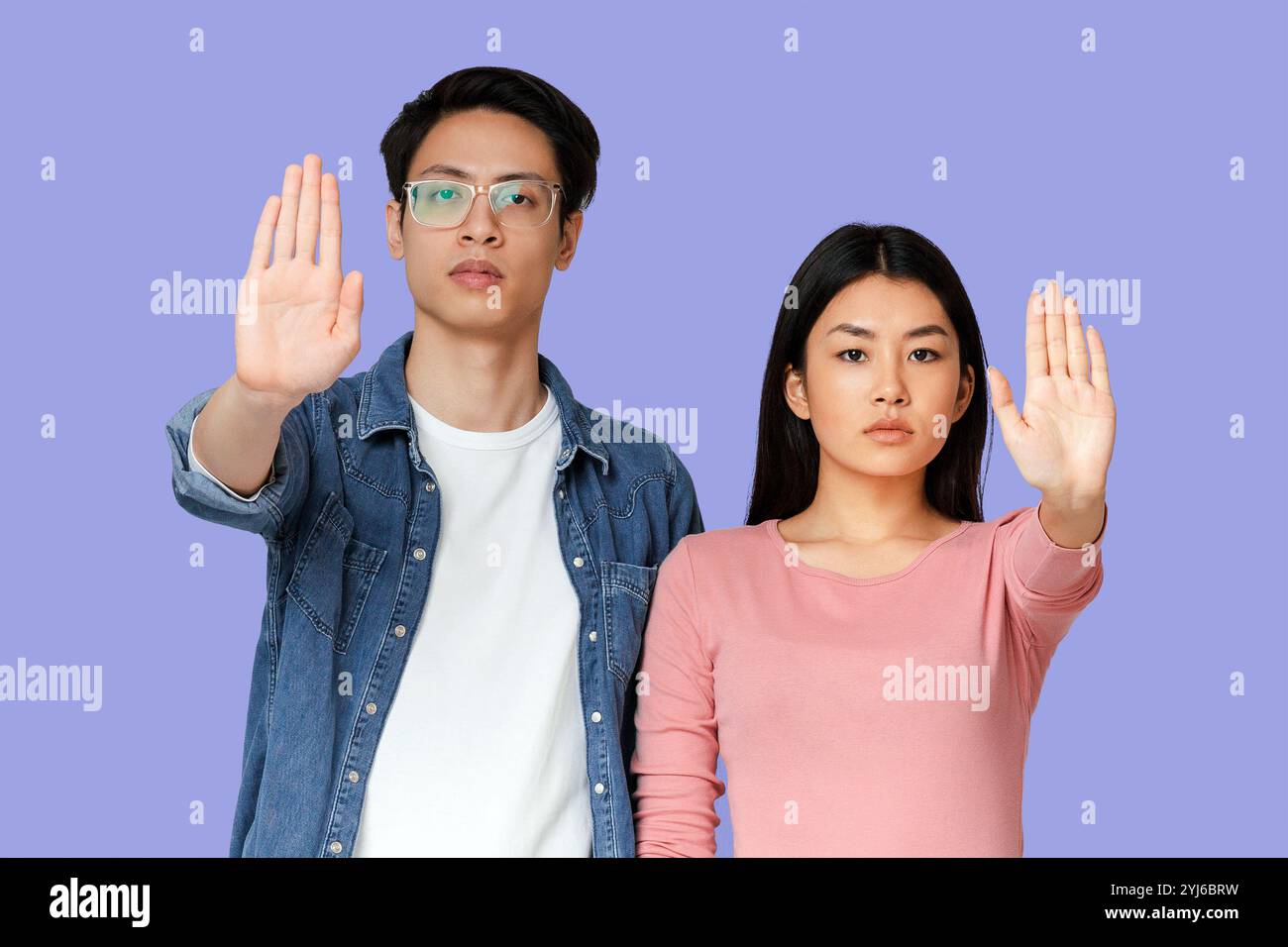 Young asian couple standing over grey studio background, doing stop sign, defense gesture Stock Photo