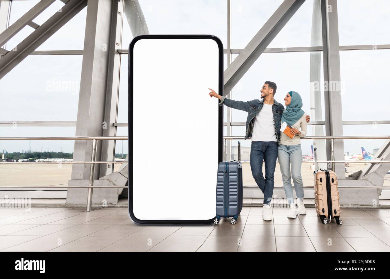 A Muslim couple stands in an airport terminal, holding luggage and a ...