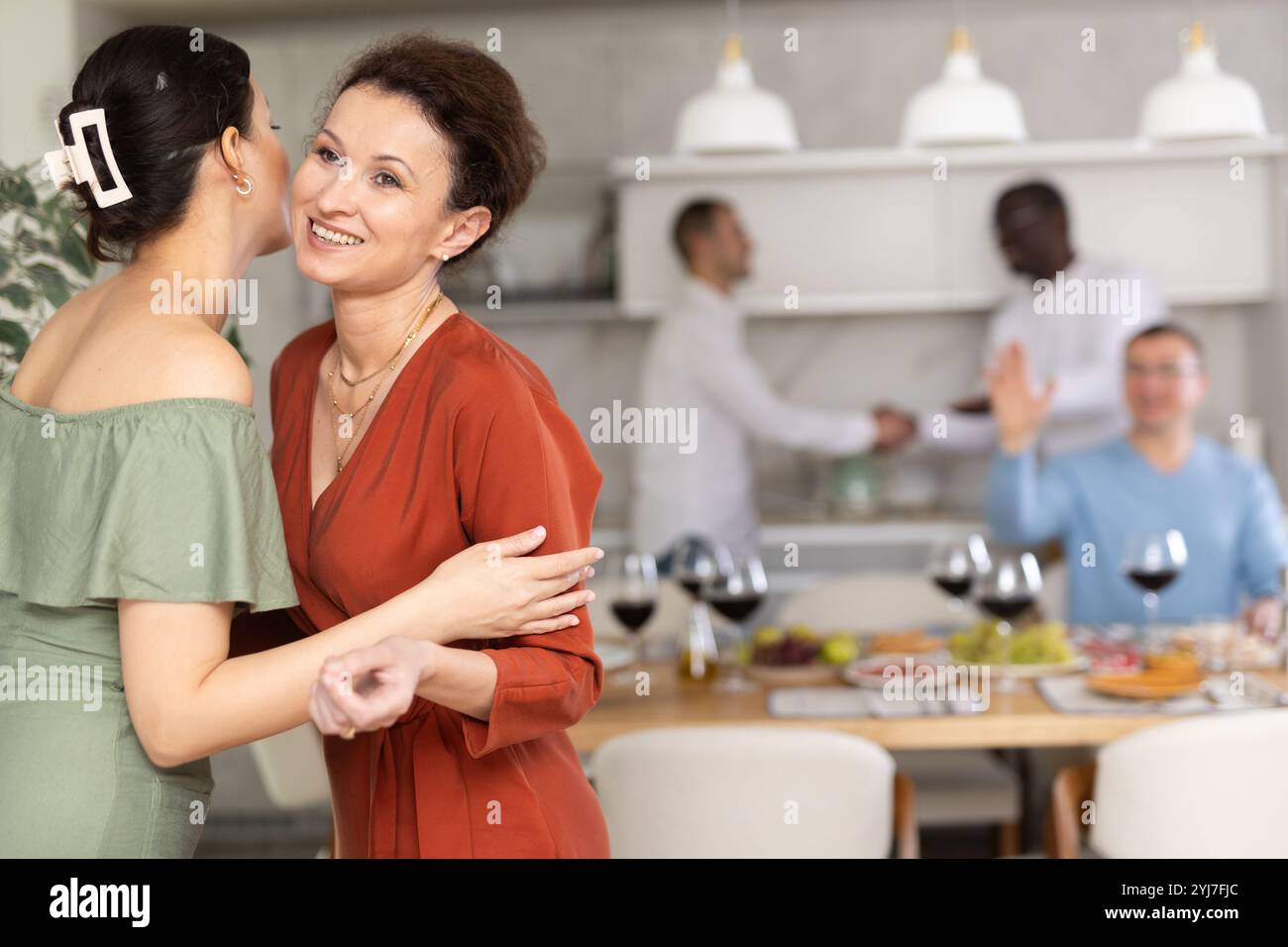 Women greet each other with kiss on cheek before festive dinner. Men ...