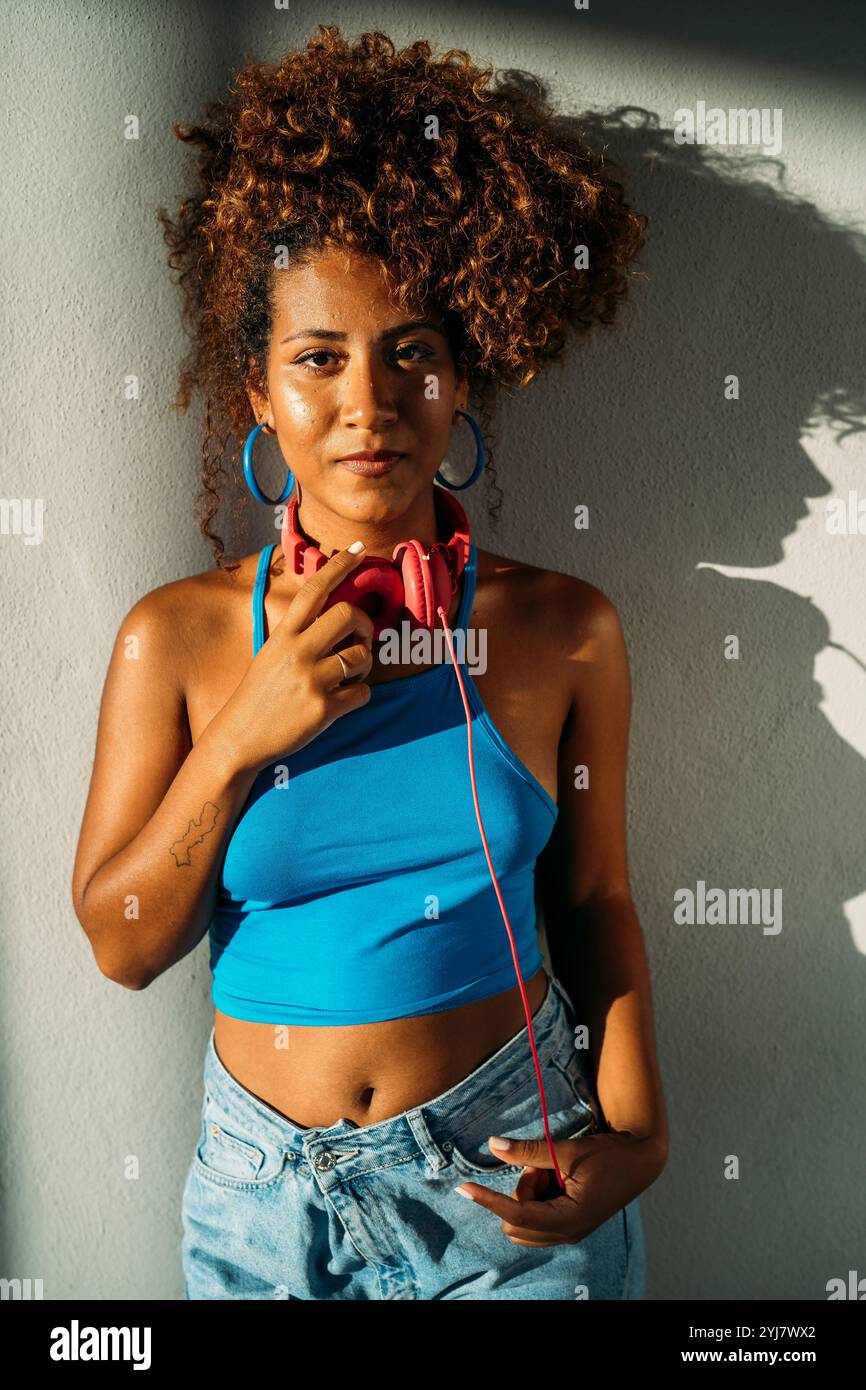 Young woman posing with headphones is touching her neck Stock Photo - Alamy