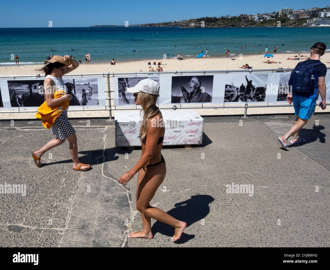 Pedestrians walk past a Head On Photo Festival exhibition hanging at Bondi beach, Sydney NSW, Australia Stock Photo