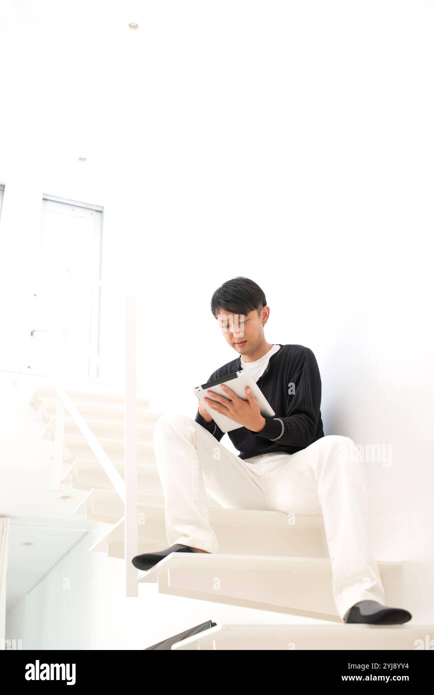 Man sitting on stairs using tablet PC Stock Photo - Alamy