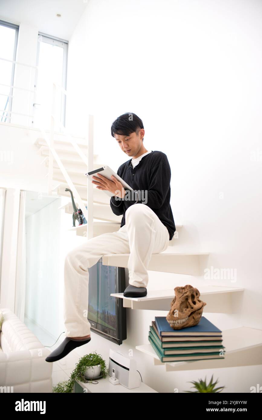 Man sitting on stairs using tablet PC Stock Photo - Alamy