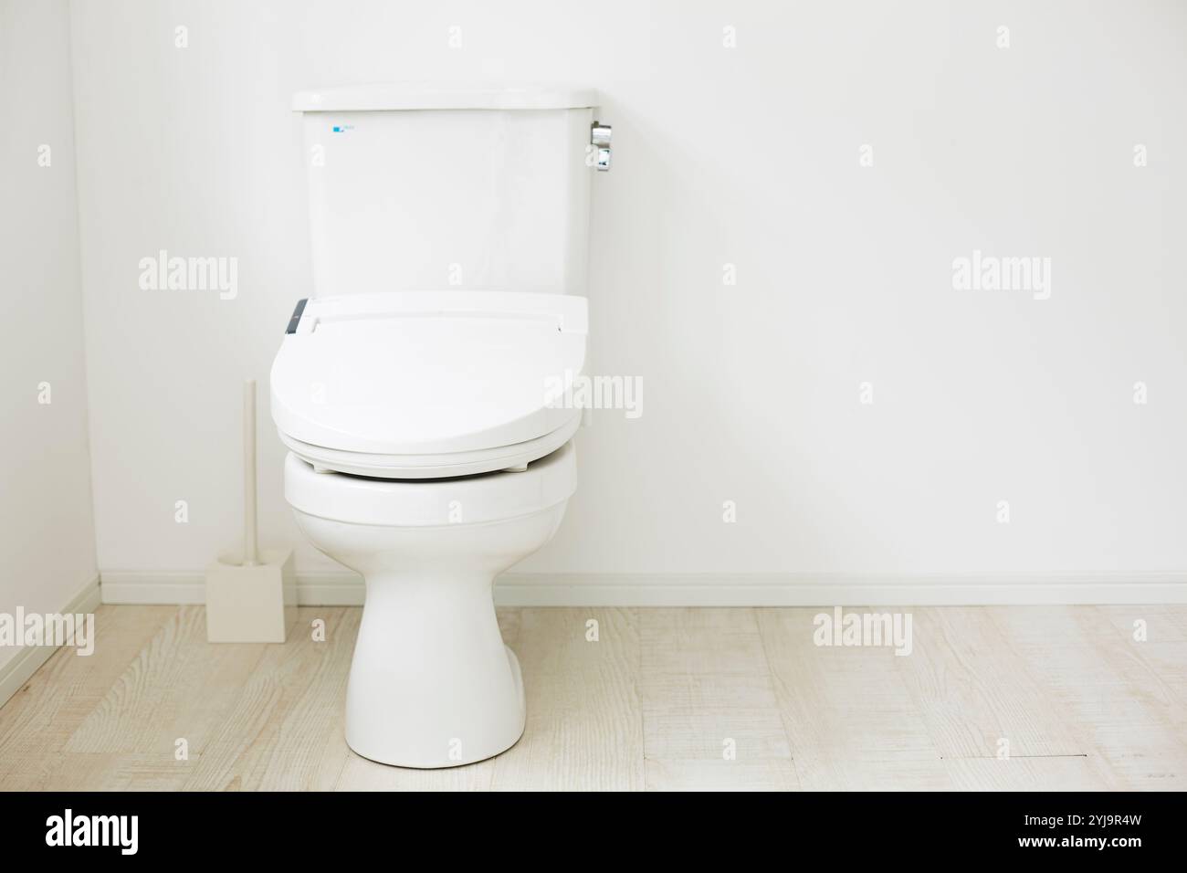 Toilet in a space with white floor and walls Stock Photo