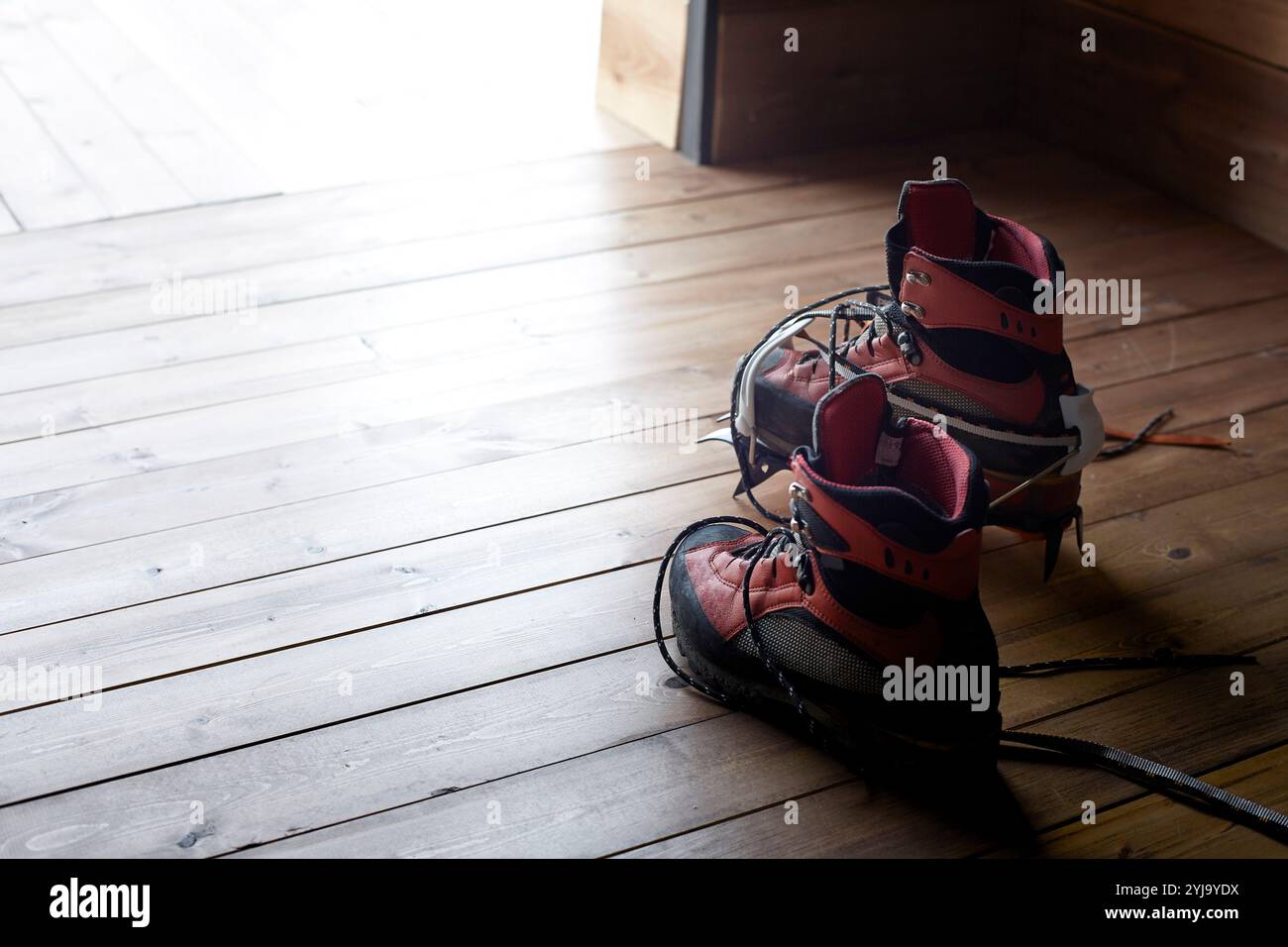 Trekking shoes with crampons placed on the floor of the mountain lodge Stock Photo