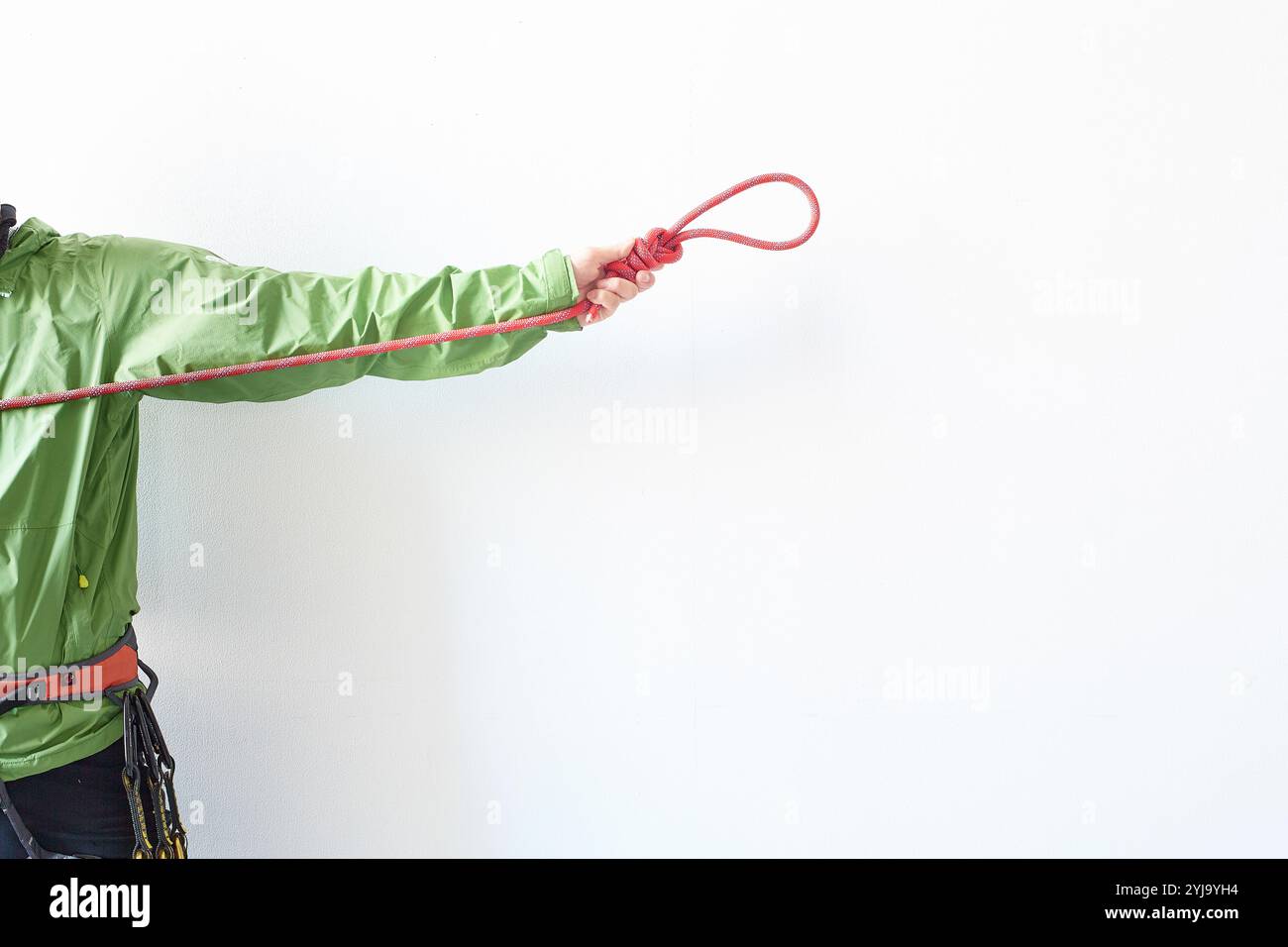 Climber holding and pulling a tied rope in front of a white wall Stock ...