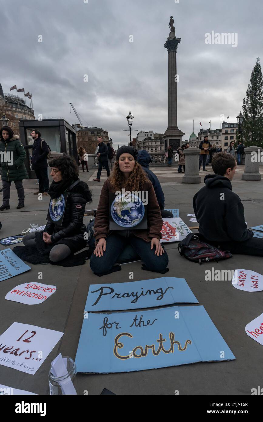 London, UK. Protesters from the Dharma Action Network meditated in Trafalgar Square and handed out flyers calling for people and governments to take effective actions to combat climate change suggesting people move their money out of banks investing in fossil fuels, get informed by reading the IPCC report on global warming and join them and other groups including Friends of the Earth, Greenpeace or take action with Extinction Rebellion. Stock Photo