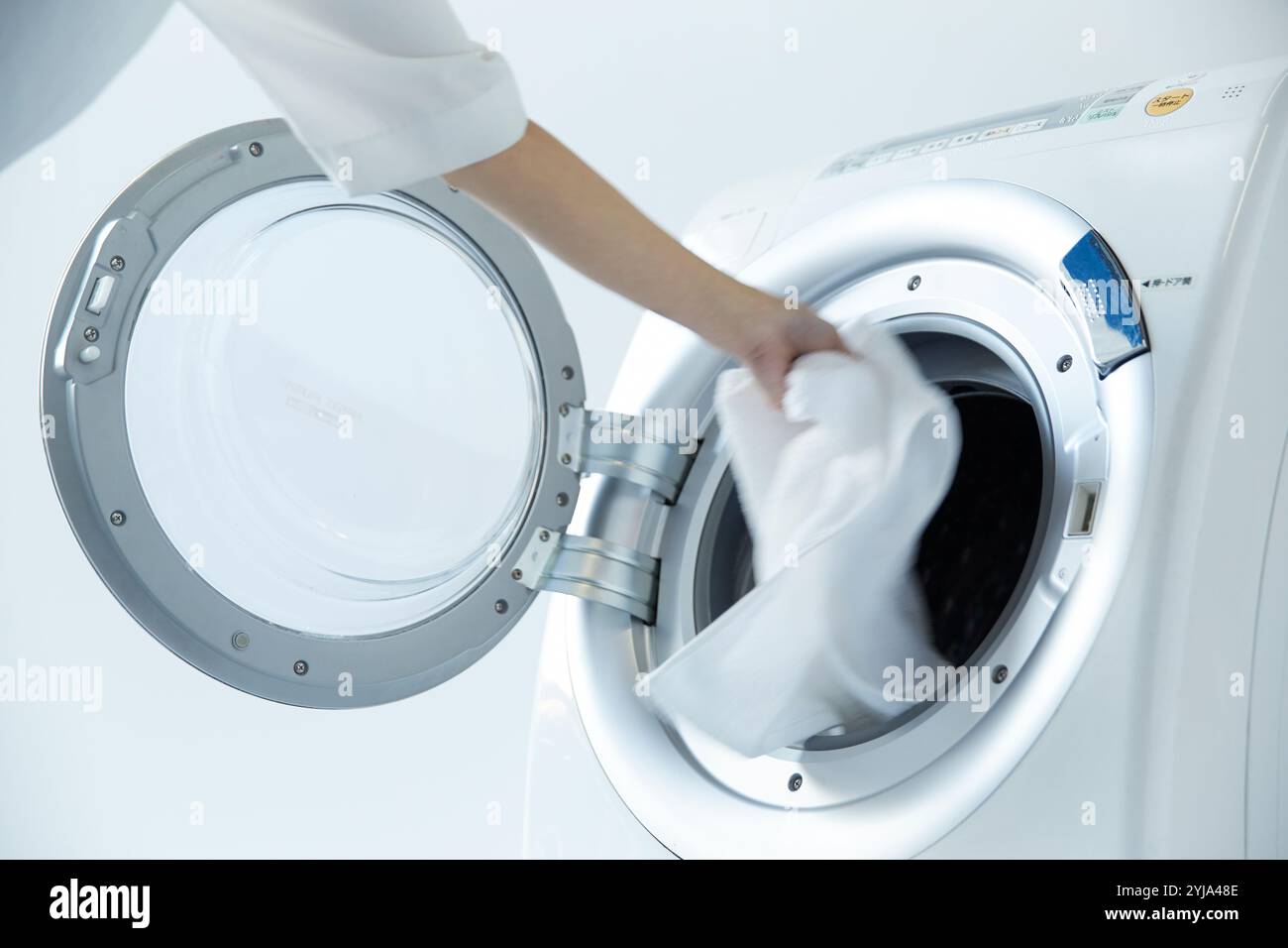 Woman's hand loading laundry into drum washing machine Stock Photo - Alamy