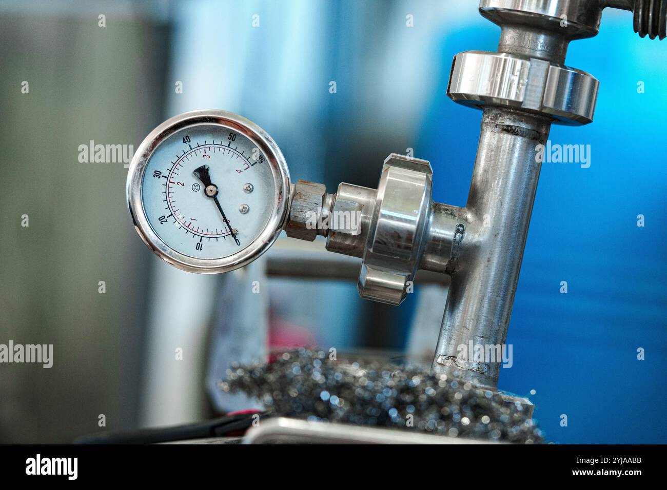 A pressure gauge is attached to a metal pipe in a factory setting Stock ...