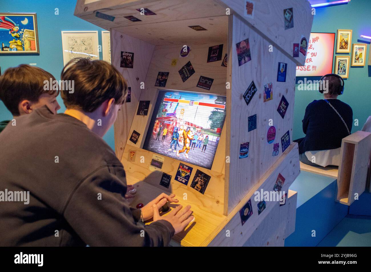 Jugendliche spielen retro Videospiel in der Ausstellung Superheroes im NRW Forum, Düsseldorf *** Young people play retro video games in the Superheroes exhibition at the NRW Forum, Düsseldorf Stock Photo