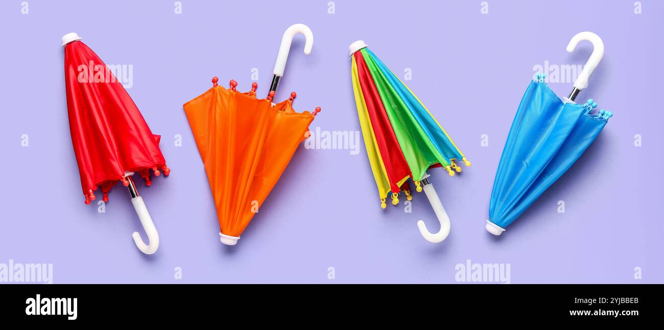 Different umbrellas on lilac background, top view Stock Photo