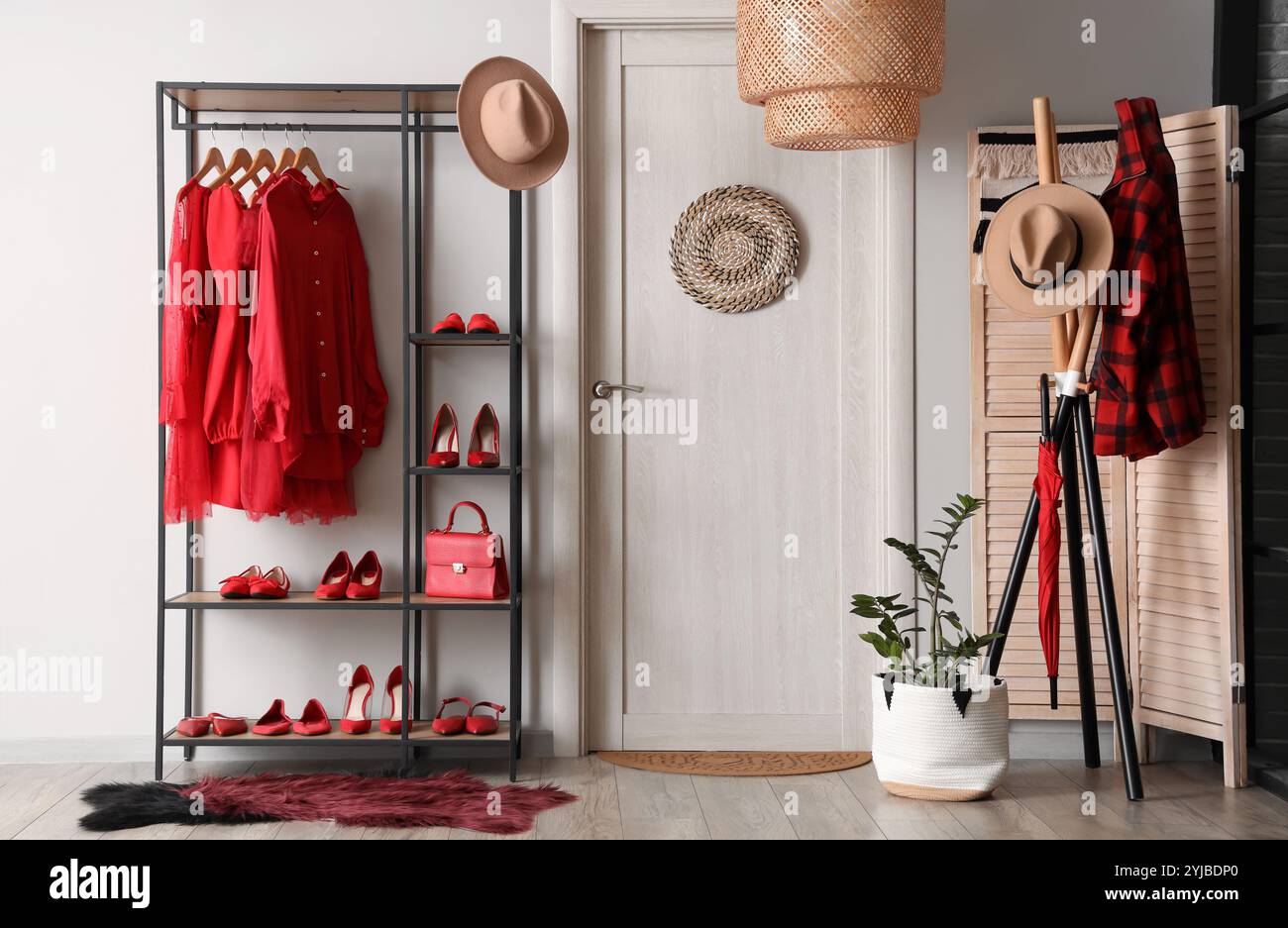 Rack of stylish red clothes with female shoes on shelves near white ...