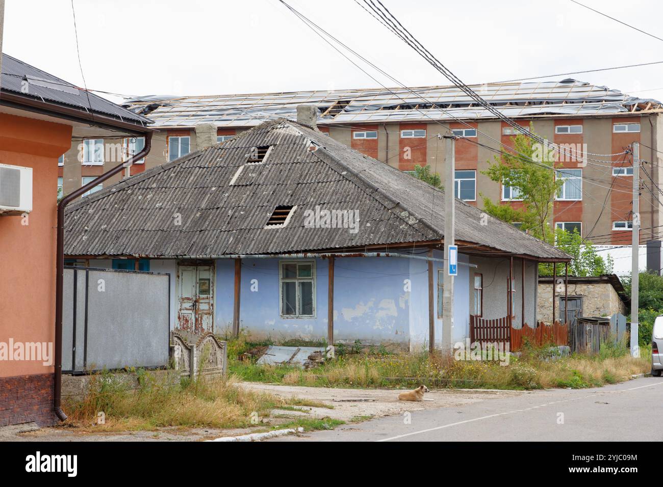 Hurricane wind effects. Broken roofs. Two sheets of slate were torn from roof of a small house and entire roof on a five-story building. Then cellopha Stock Photo