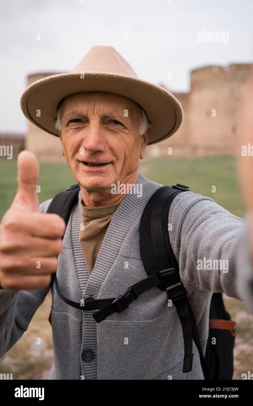 Retired man tourist traveler influencer taking selfie photo on mobile phone camera in ancient fortress traveling vlog Stock Photo