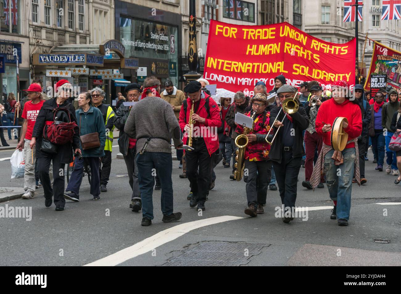 A rally in Trafalgar Square including many  from London's international and migrant communities celebrates  International Workers Day. Some held flags and banners on the plinth of  Nelson's Column  while others listened to the speeches by a number of  trade unionists and activists and included a short silence in memory of  Mehmet Aksoy who was killed in Syria whilst filming with Kurdish  fighters and had spoken for the Kurds at previous events. At the end of  the rally there was a speech by Brixton Ritzy trade unionist Kelly  Rogers victimised by Picturehouse and the various precarious workers Stock Photo