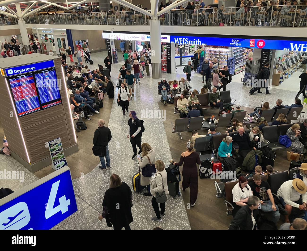 Crowded airport departure lounge, from upper level looking down with people looking at the gate information on the board waiting for flight Stock Photo