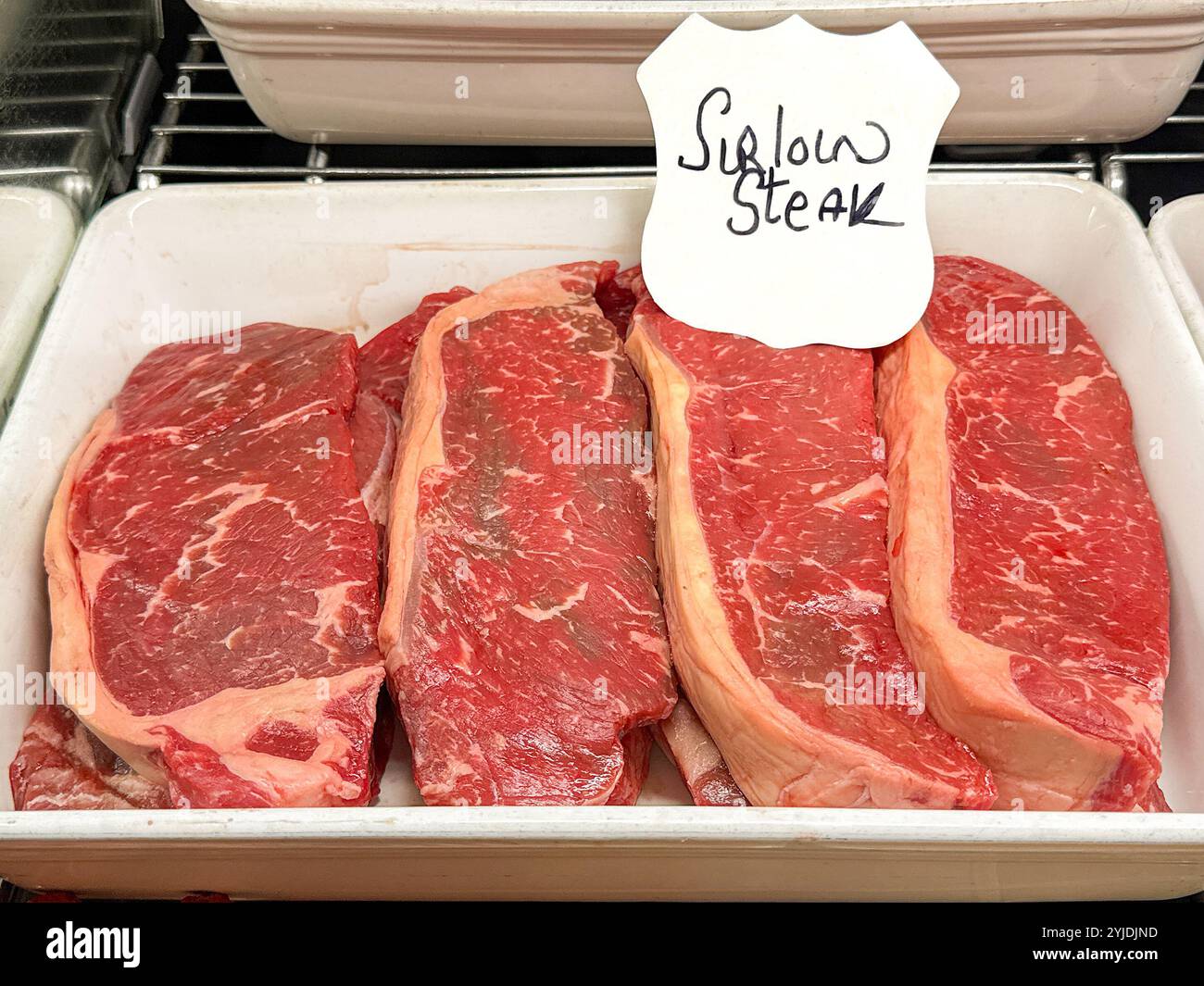 Fresh raw sirloin steaks on display in the chilled counter of a restaurant - Smartphone Captured Stock Image